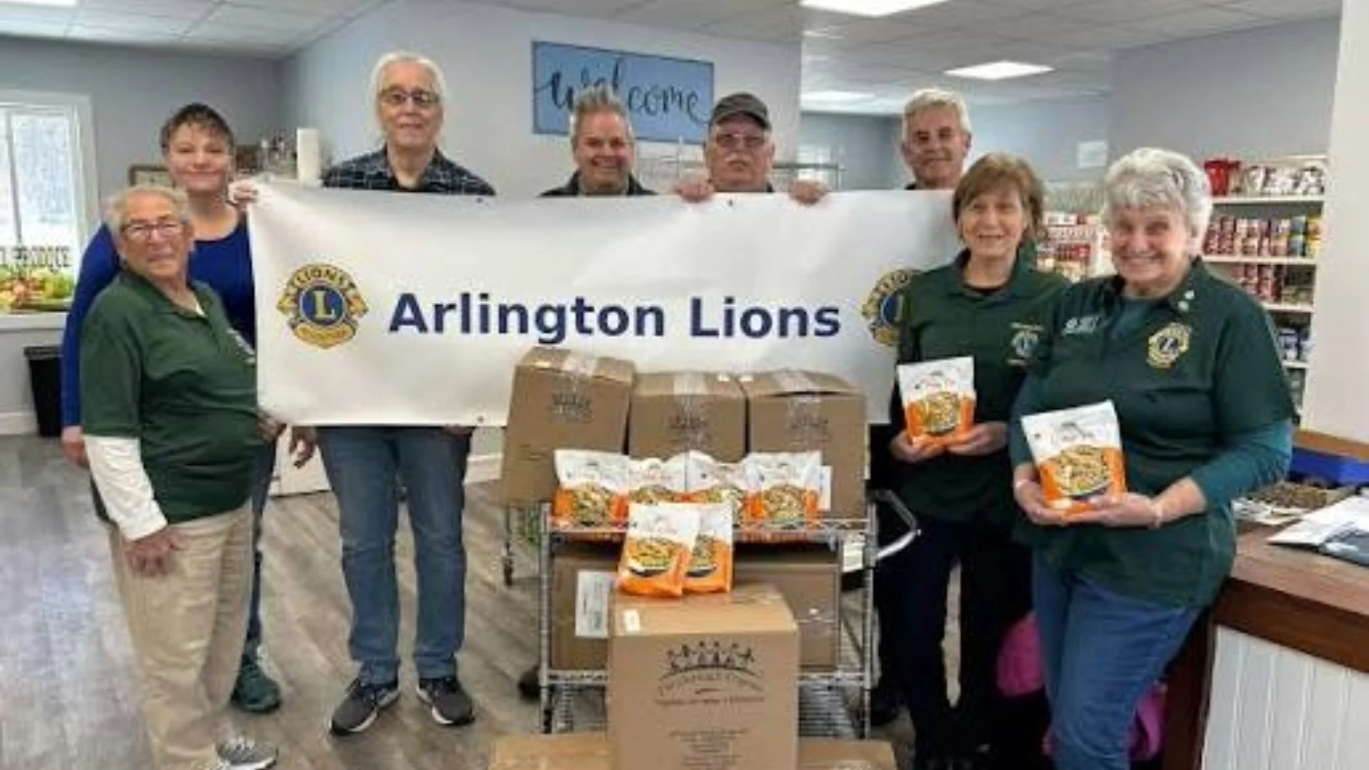 Jacksonville Arlington Lions Club members holding an Arlington Lions banner at a community food drive