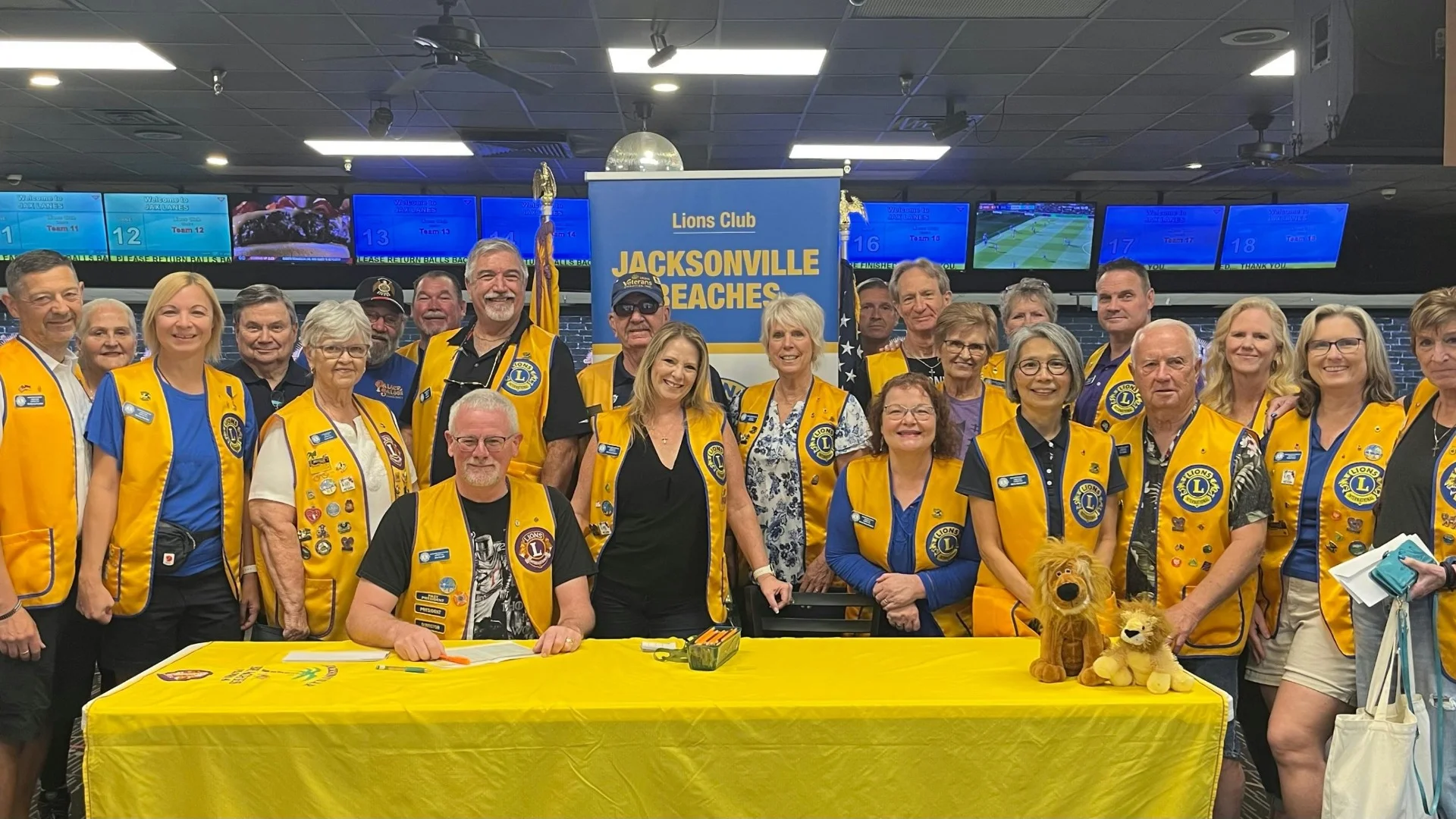 Lions Club Jacksonville Beach members gathered at a club event at Bowlarama, many wearing the distinctive gold Lions Club vests